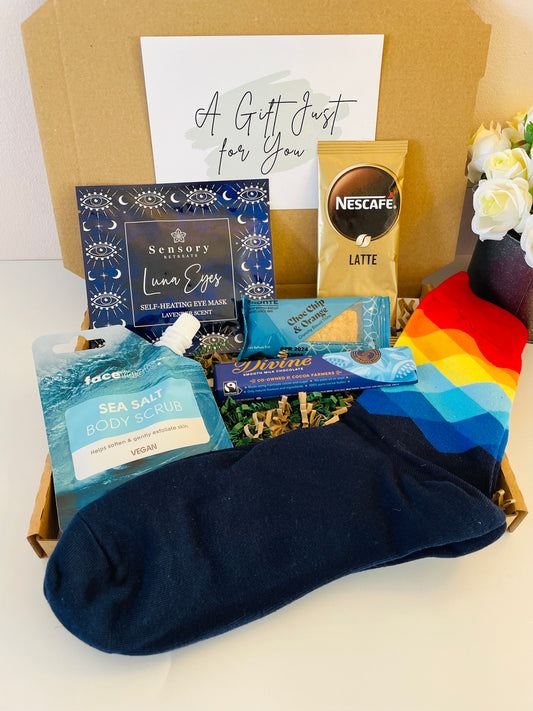 A letterbox gift filled with a variety of treats and self care. Mens Socks, a shower body scrub, lavender self heating eye mask, pack of 2 biscuits, divine milk chocolate bar and a hot drink of your choice. Comes with an option of a gift card and a personalised message, delivered straight to the recipient’s door.