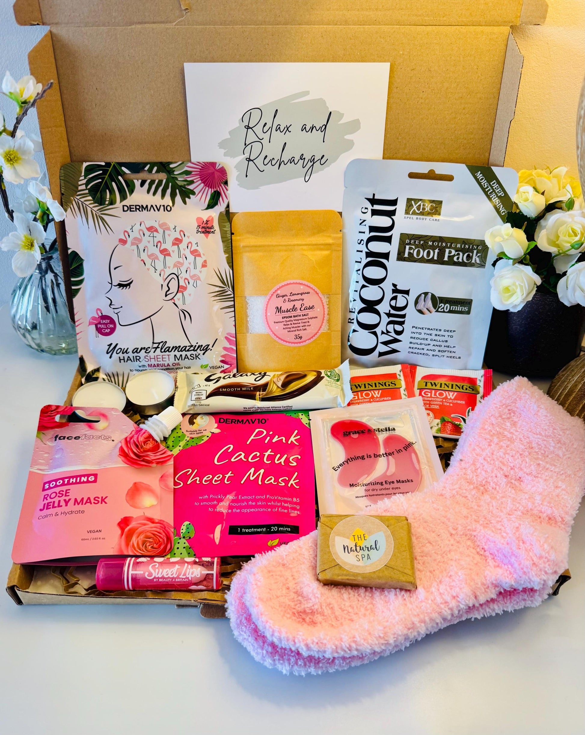 Pamper gift box includes pink cosy socks, scented lip balm, travel soap, rose jelly face mask, face sheet mask, hair sheet mask, bath salts, coconut foot pack, pink under eye masks, galaxy chocolate bar hot drink options. Comes with the option to add your own personalised message ready to send direct to the recipient