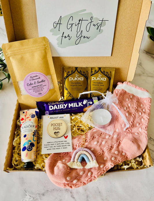 Our Hug in a Box Gift includes pink themed socks, a keepsake hug token, Cadbury chocolate bar, bath salts, hand cream, rainbow keyring, tea light candle in an organza bag and drink options. comes with your own personalised gift message ready to send direct to the recipient