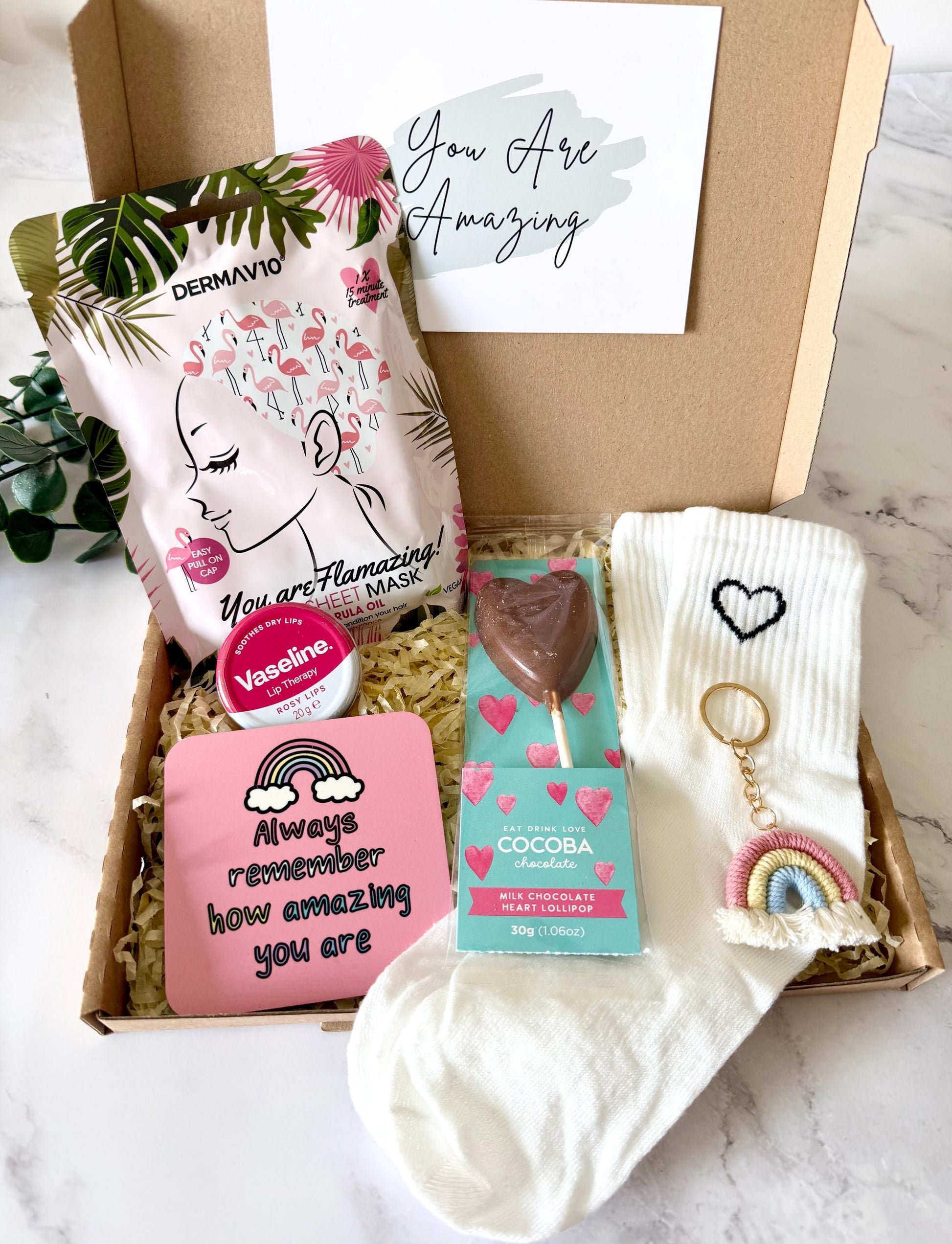 our your amazing gift box includes socks, pink rainbow keyring, ‘always remember how amazing you are’ coaster, milk chocolate heart lolly, hair sheet mask, pink Vaseline tin. The gift is ready to send direct to the recipient and includes your chosen gift card and a personalised message